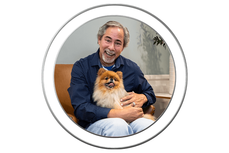 Smiling dental patient holding a puppy at J.P Prosthodontics in Fullerton, CA