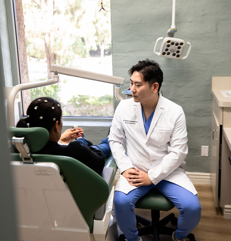 Dr. Joon Park talking with a dental patient at J.P Prosthodontics in Fullerton, CA