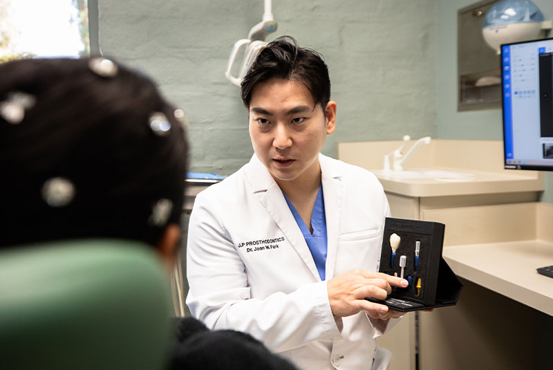 Dr. Joon Park explaining the benefits of dental implants at J.P Prosthodontics in Fullerton, CA